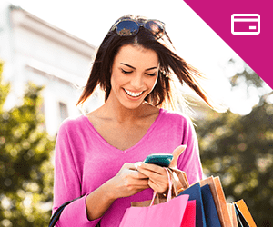 A young woman holding shopping bags looking at a smartphone