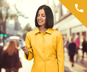 A professional woman standing and smiling while using a cell phone